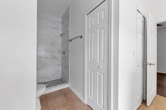 bathroom with a shower stall, toilet, baseboards, and tile patterned floors