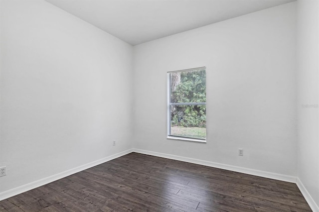 unfurnished room with baseboards and dark wood finished floors