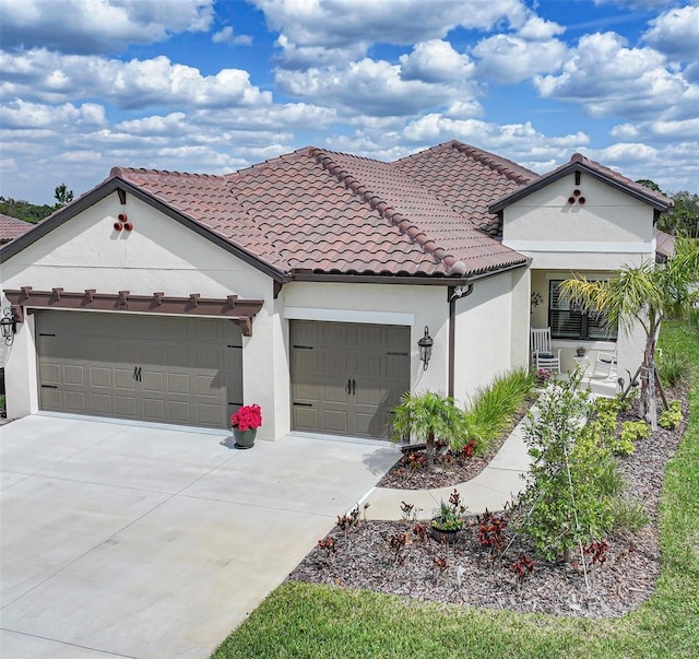 mediterranean / spanish-style home with a tiled roof, an attached garage, and stucco siding