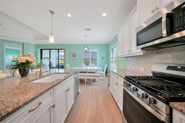 kitchen featuring appliances with stainless steel finishes, white cabinetry, a sink, and backsplash