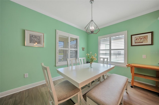 dining space with an inviting chandelier, baseboards, wood finished floors, and ornamental molding