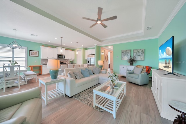 living room featuring light wood-style flooring, visible vents, and ornamental molding