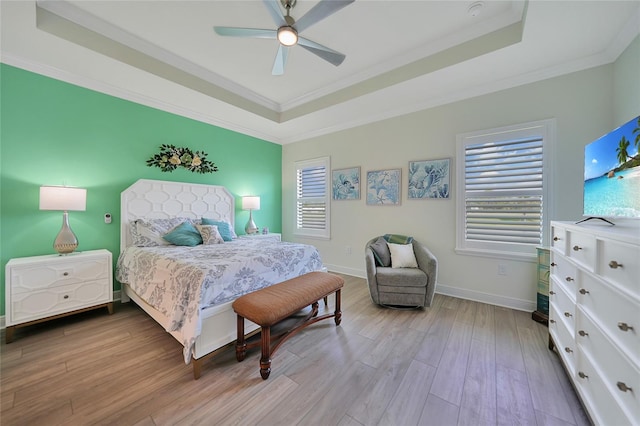 bedroom featuring a tray ceiling, crown molding, baseboards, and wood finished floors