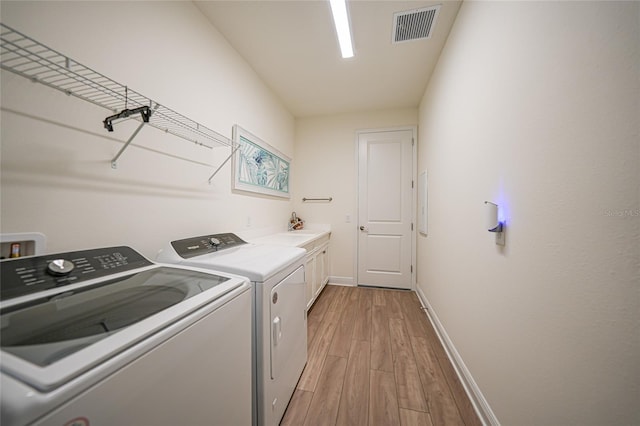 laundry room featuring cabinet space, visible vents, baseboards, light wood-style flooring, and independent washer and dryer