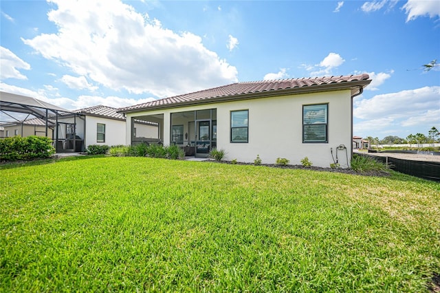 back of property featuring a yard, a tile roof, and stucco siding