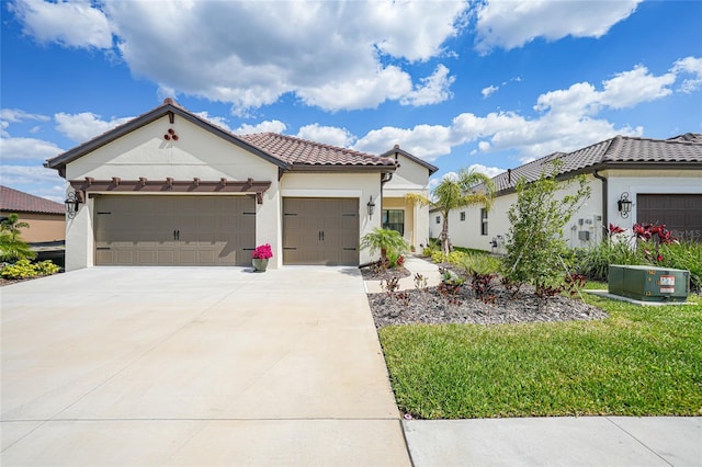 mediterranean / spanish home featuring stucco siding, a garage, driveway, a tiled roof, and a front lawn