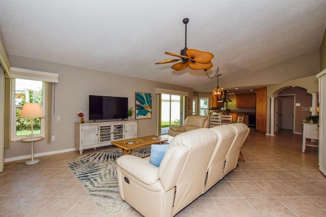 living room featuring arched walkways, light tile patterned floors, a wealth of natural light, and lofted ceiling