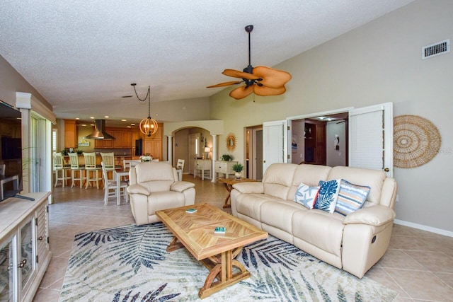 living area featuring light tile patterned floors, visible vents, arched walkways, and a textured ceiling