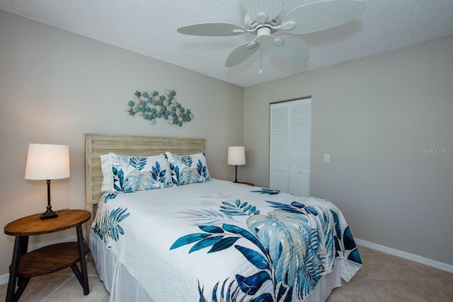 bedroom featuring baseboards, ceiling fan, a closet, a textured ceiling, and tile patterned floors