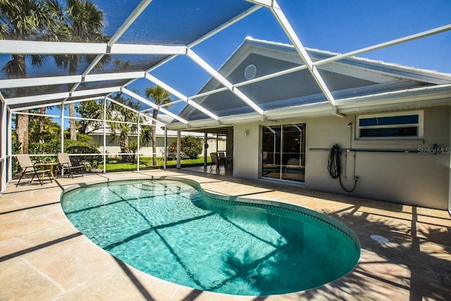 outdoor pool featuring glass enclosure and a patio