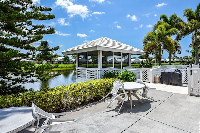 view of patio / terrace with outdoor dining space, a water view, and a sunroom