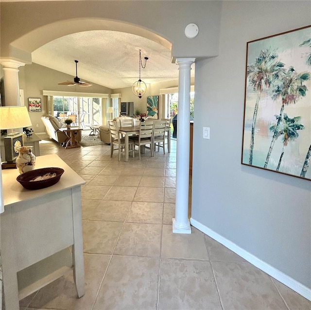 dining space featuring a textured ceiling, decorative columns, baseboards, ceiling fan, and vaulted ceiling