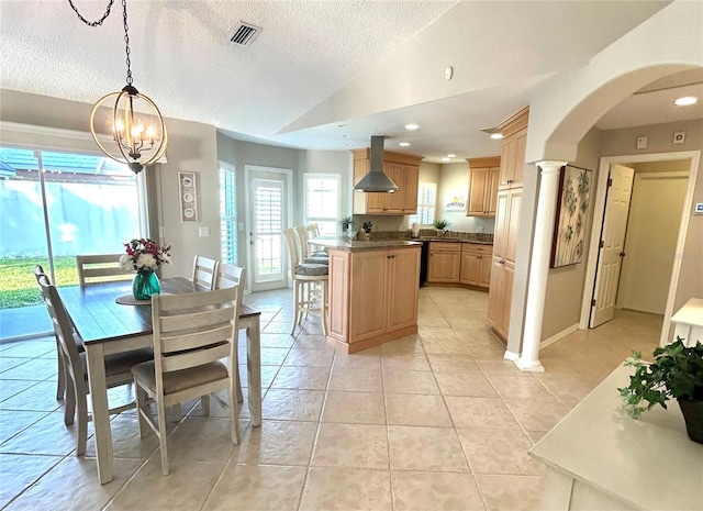 kitchen featuring visible vents, vaulted ceiling, light tile patterned flooring, a textured ceiling, and wall chimney exhaust hood