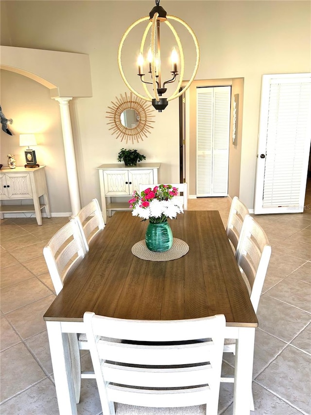 dining space featuring tile patterned flooring, a notable chandelier, arched walkways, and ornate columns