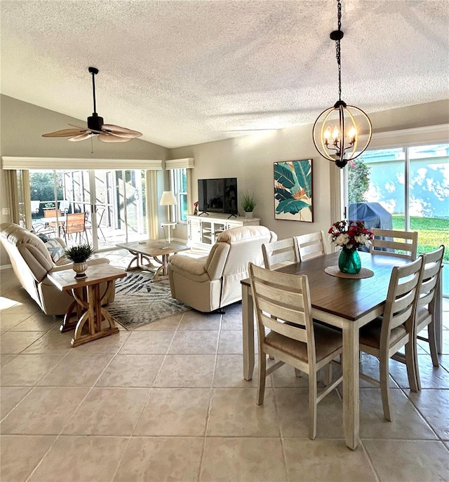 dining room with light tile patterned floors, ceiling fan with notable chandelier, a textured ceiling, and vaulted ceiling