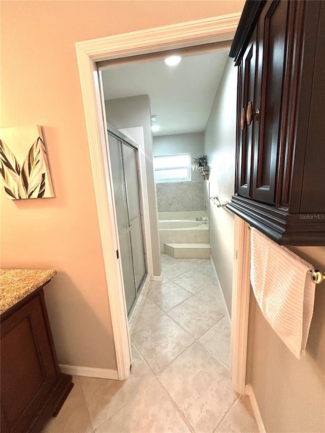 bathroom featuring tile patterned floors, a garden tub, a stall shower, baseboards, and vanity