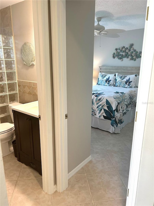 bathroom featuring a textured ceiling, toilet, a ceiling fan, and tile patterned flooring