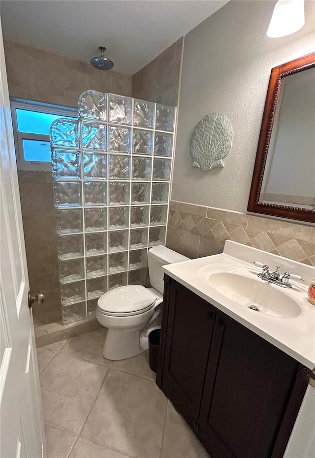 full bath featuring toilet, tile walls, tile patterned flooring, walk in shower, and vanity