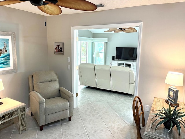 living area featuring light tile patterned flooring, visible vents, and ceiling fan