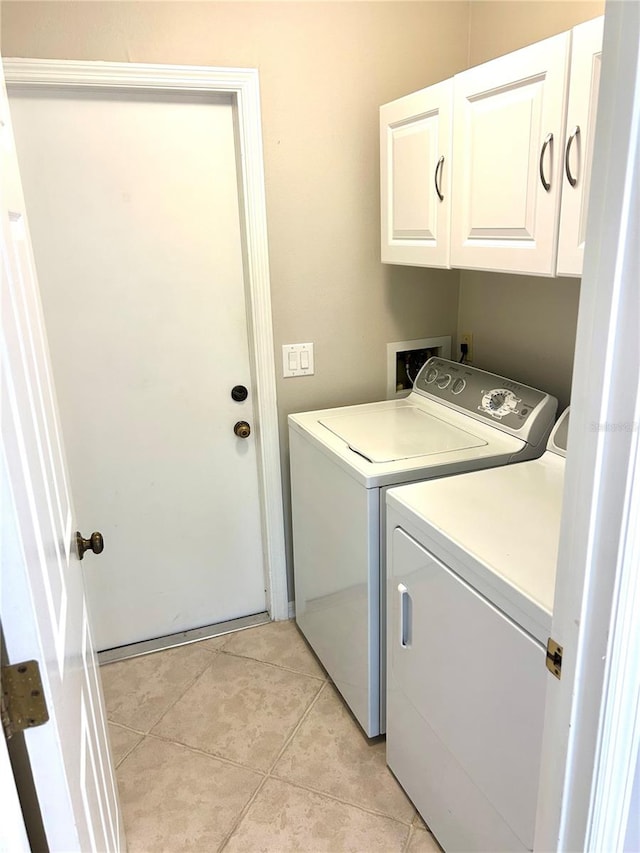 laundry area featuring light tile patterned floors, cabinet space, and washing machine and dryer