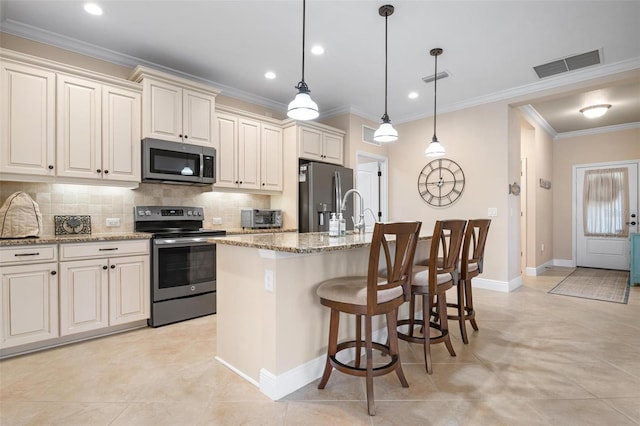 kitchen featuring visible vents, decorative backsplash, ornamental molding, a kitchen island with sink, and stainless steel appliances