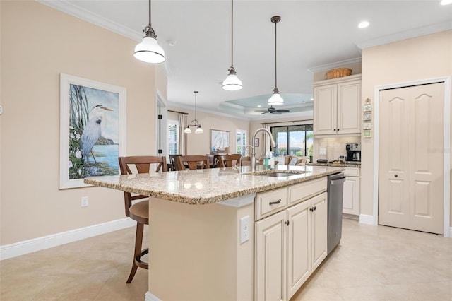 kitchen with light stone counters, a tray ceiling, crown molding, a breakfast bar area, and a sink