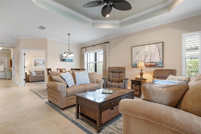 living area with light tile patterned floors, ceiling fan with notable chandelier, visible vents, a tray ceiling, and crown molding