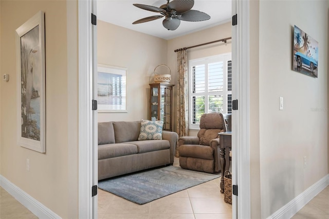 living area featuring a ceiling fan, baseboards, and light tile patterned floors