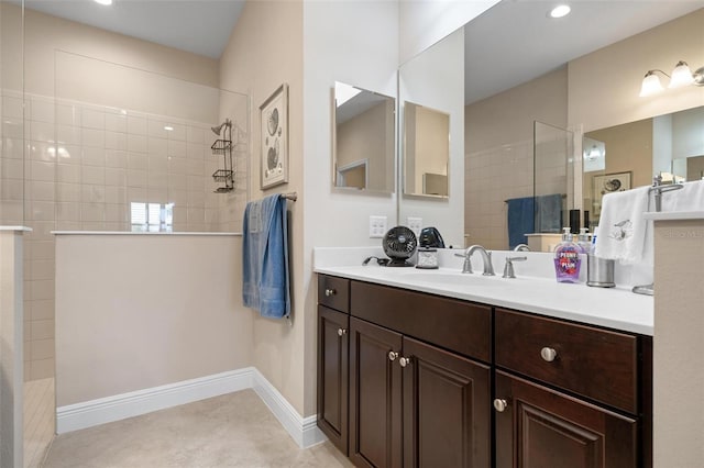 full bath with tile patterned flooring, baseboards, a walk in shower, and vanity