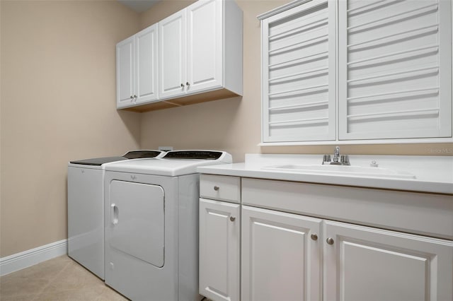 washroom with light tile patterned floors, cabinet space, a sink, washer and dryer, and baseboards