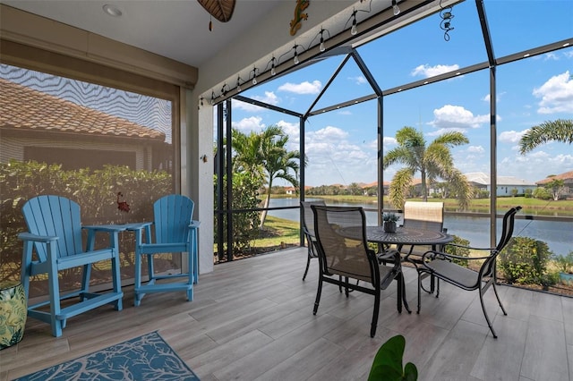 sunroom / solarium featuring a water view and ceiling fan