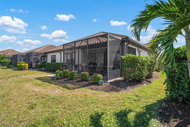 back of property with glass enclosure, a lawn, and a tile roof