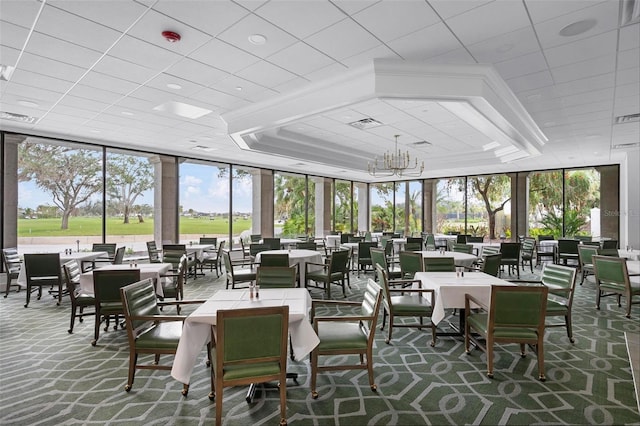 carpeted dining area with a chandelier, a raised ceiling, and visible vents