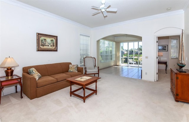 living area featuring light carpet, ornamental molding, arched walkways, and a ceiling fan