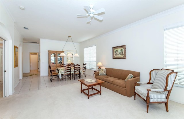 living area featuring light tile patterned floors, light colored carpet, visible vents, ornamental molding, and ceiling fan