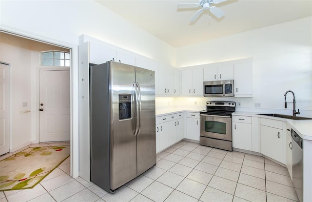 kitchen featuring light tile patterned floors, stainless steel appliances, light countertops, white cabinetry, and a sink