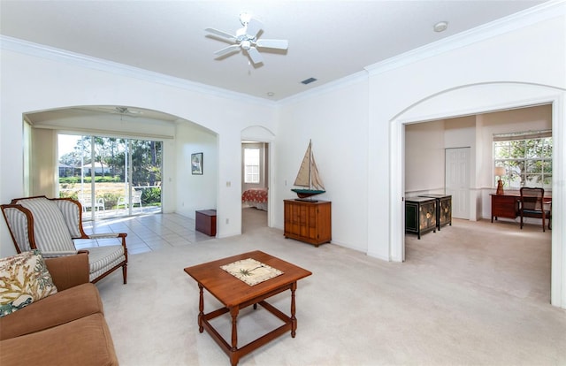 living area with arched walkways, light carpet, visible vents, a ceiling fan, and crown molding