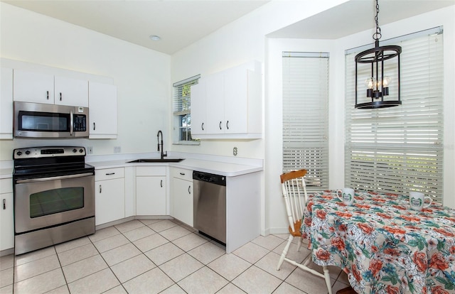 kitchen with white cabinets, appliances with stainless steel finishes, light countertops, a sink, and light tile patterned flooring