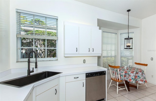 kitchen featuring light tile patterned floors, a sink, light countertops, stainless steel dishwasher, and decorative light fixtures