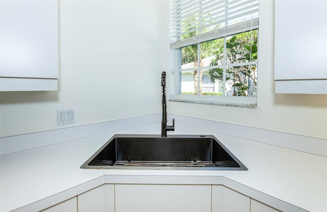 room details with light countertops, a sink, and white cabinets