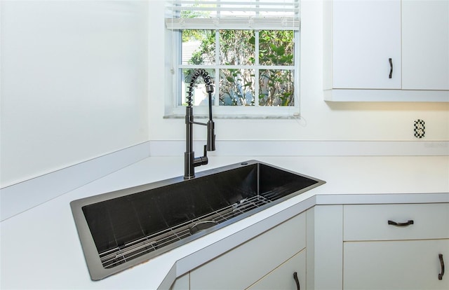 interior details featuring light countertops, a sink, and white cabinetry