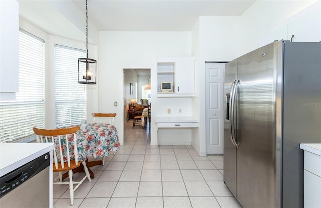 kitchen featuring stainless steel appliances, light countertops, a healthy amount of sunlight, white cabinets, and light tile patterned flooring