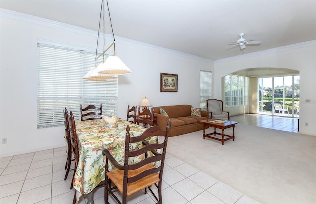 dining space with ornamental molding, arched walkways, light colored carpet, and light tile patterned floors