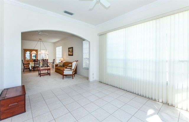 sitting room featuring arched walkways, ornamental molding, light tile patterned floors, and a ceiling fan