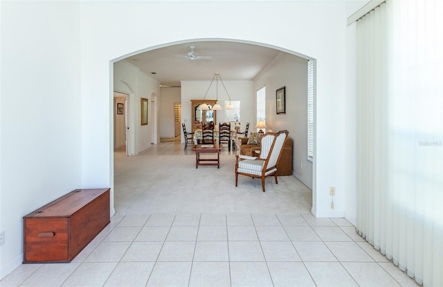 hall with ornamental molding, arched walkways, light carpet, and light tile patterned floors