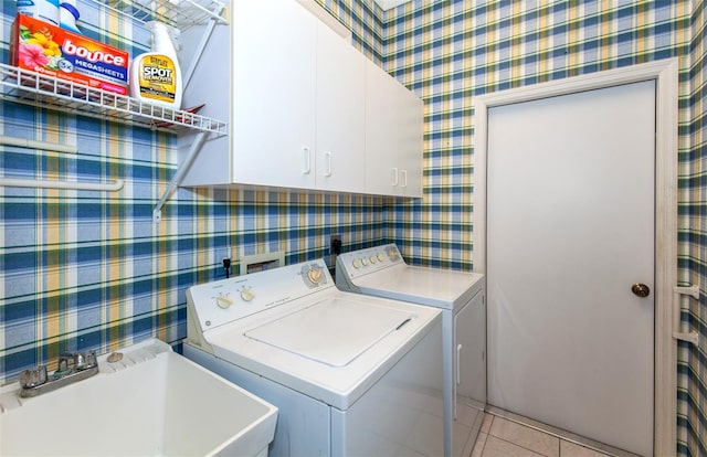 laundry room with washer and clothes dryer, cabinet space, light tile patterned flooring, a sink, and wallpapered walls