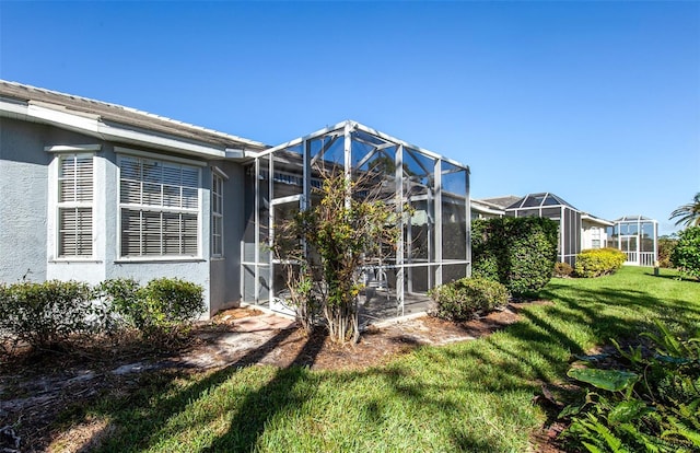 exterior space featuring a lanai, a lawn, and stucco siding