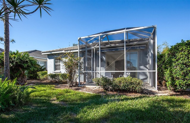 rear view of property featuring a lanai and a yard