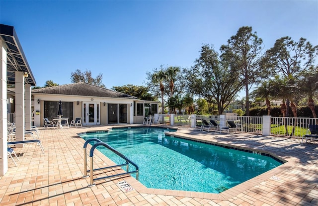 community pool with a patio, french doors, and fence