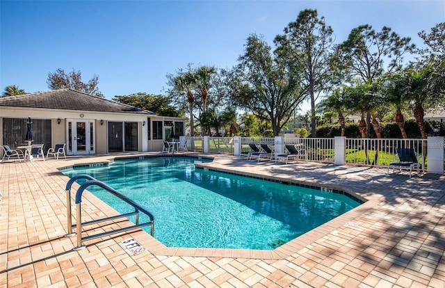 pool featuring french doors, a patio area, and fence